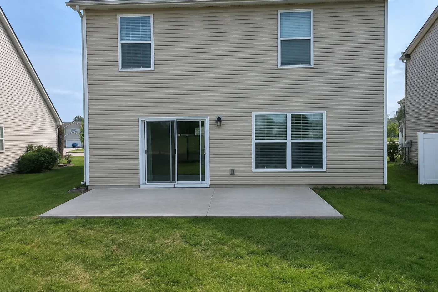 The back of a two-storey house with a bare concrete patio
